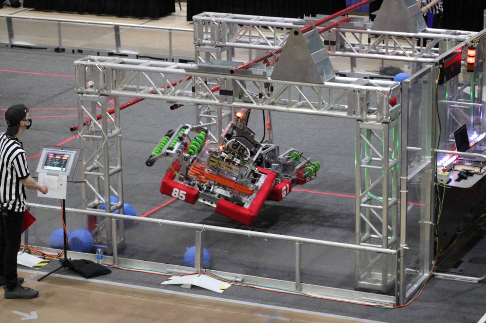 Two robots hang from a bar at the end of a match